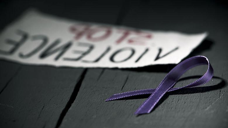 a purple ribbon and a sign reading Stop Violence